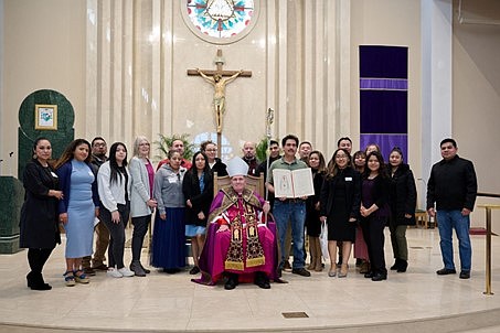 Un miembro del equipo del Rito de Iniciación Cristiana para Adultos de la parroquia sostiene el Libro de Elegidos mientras se nombran los nombres de los catecúmenos de su parroquia durante el Rito de Elección. Foto de Mike Ehrmann